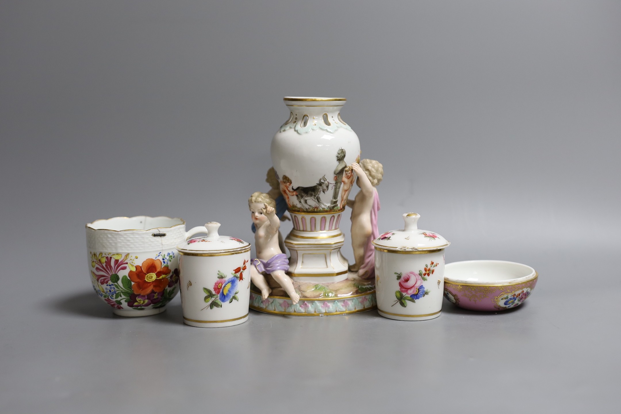 A Meissen cherub centrepiece, a similar cup and box base, together with two Meissen style jars and covers, centrepiece 16 cms high